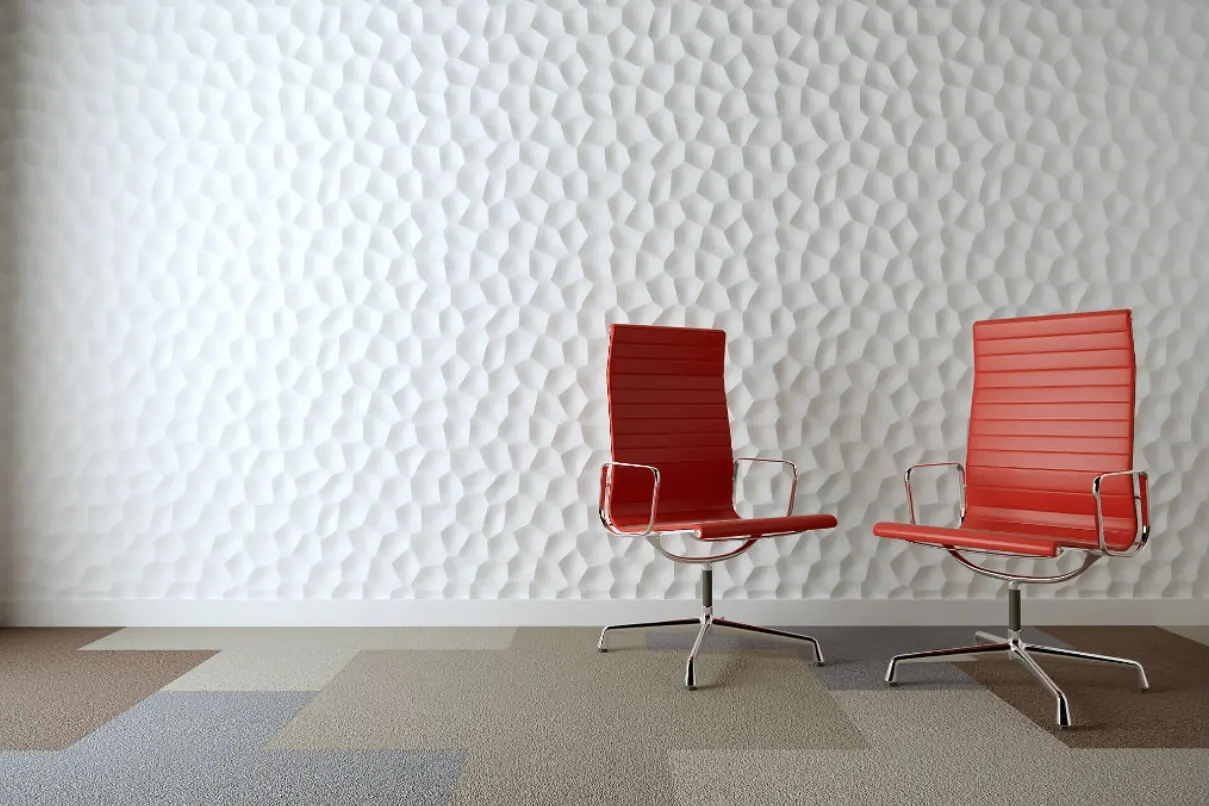 Twee rode bureaustoelen tegen een witte 3D-wand met kiezelreliëf