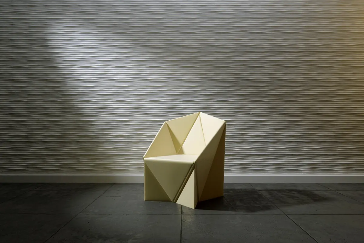 Origami-fauteuil tegen een 3D-wand met dichte horizontale ribbels